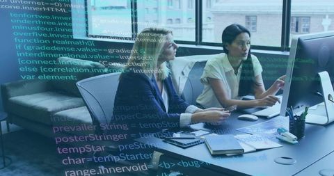 Women collaborating on software development at modern office desk with code overlay