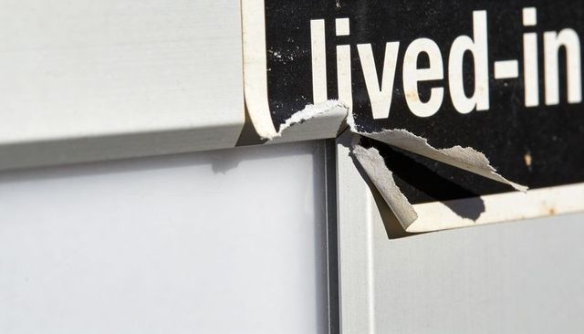 Peeling black-and-white adhesive sign curling on metal frame closeup for texture