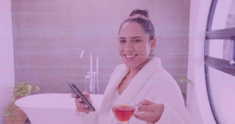 Woman in White Robe Relaxing with Phone and Tea in Modern Bathroom