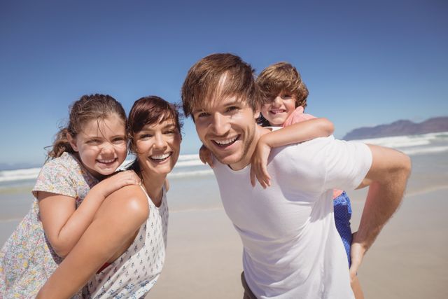 Family of four smiling and enjoying time together at the beach. Perfect for advertisements, travel brochures, family-oriented products, and lifestyle blogs.