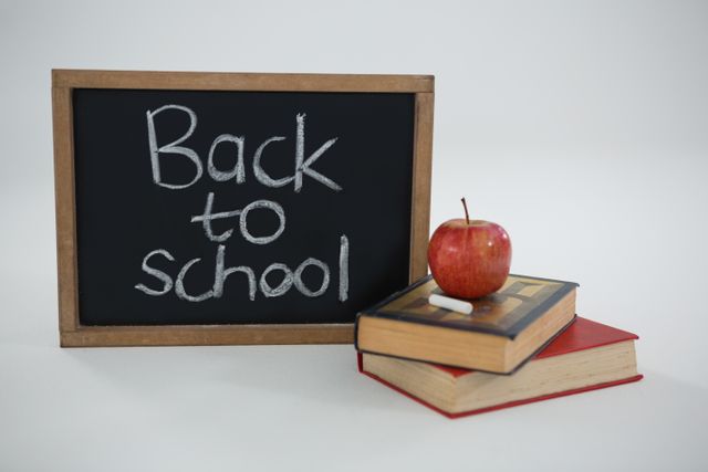 Close-up of back to school text with apple and books on white background