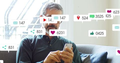 Senior man scrolling smartphone on couch with social media notification bubbles floating around