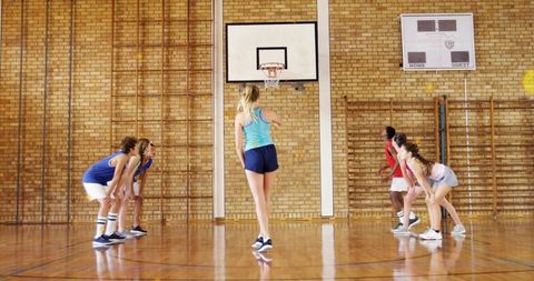 School basketball shooting free throw while teammates preparing for rebound on gym hardwood