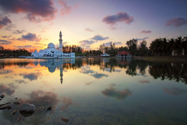 Gorgeous sunset sky with glossy mosque reflection on calm lake waters. Ideal for spiritual, calming, and travel purposes.
