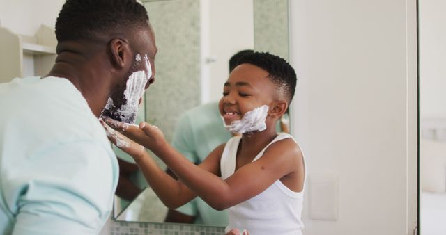 Father and son enjoying playful bonding time while shaving together in bathroom. Perfect for topics on family bonding, morning routines, parent-child relationships, and teaching life skills.