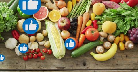 Fresh colorful produce spread with corn, tomatoes and grapes on rustic wood with thumbs-up
