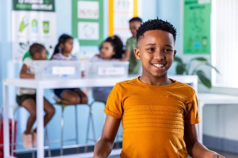 African american boy smiling in classroom during collaborative learning and recycling activity