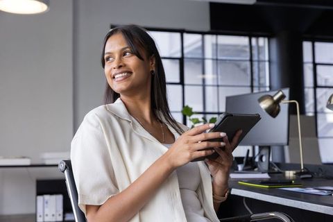 Smiling Woman with Tablet in Modern Workspace