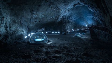 Underground blue glass dome pods with illuminated catwalk in cavern retreat