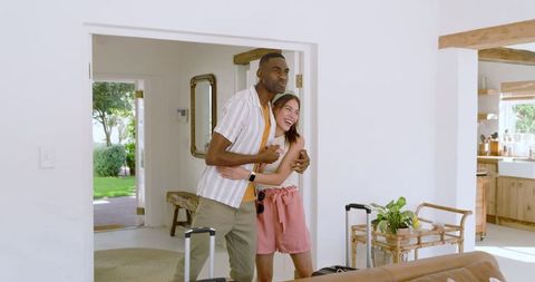 Joyful Couple Laughing in Modern Home Entryway with Luggage
