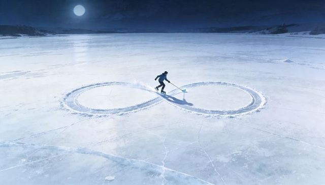 Moonlit skater clearing figure-eight on frozen lake under full moon