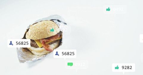 Minimal sesame cheeseburger sitting in foil with social media like and follower icons