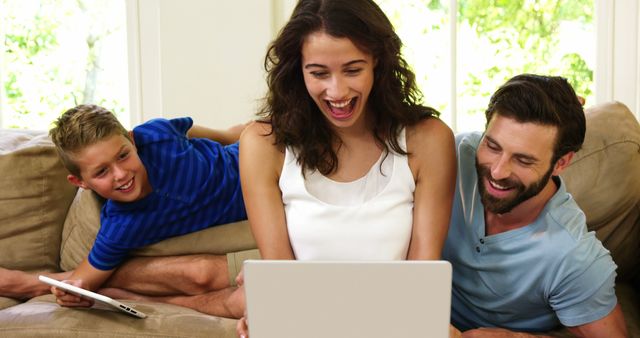 Smiling Family Enjoying Time Together on Couch with Laptop - Download Free Stock Images Pikwizard.com