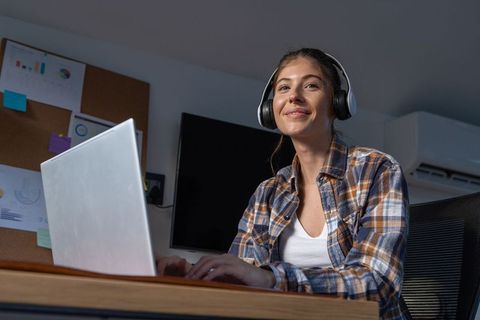 Young Woman Working Remotely from Home Office with Headset and Laptop