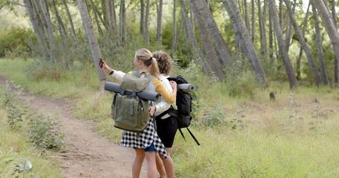 Two Women Hiking on Forest Trail with Backpacks on Relaxing Adventure