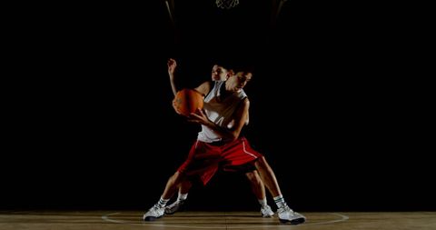Intense basketball match on dimly lit indoor court