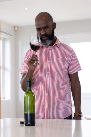 Mature Man Appreciating Fine Red Wine at Home