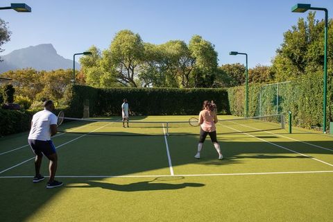 Active friends playing doubles tennis on sunny grass court