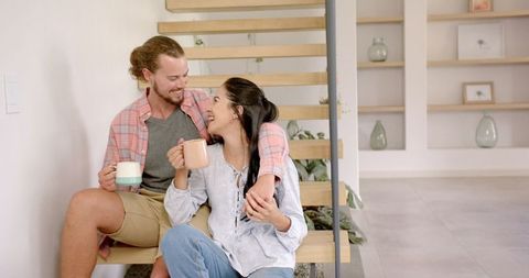 Joyful Couple Sharing Coffee on Modern Home Staircase