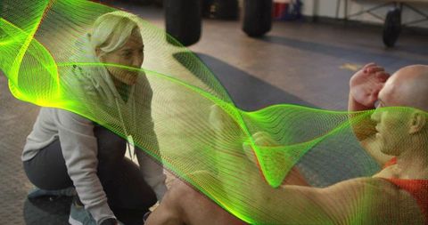 Coach assisting trainee performing sit-ups on rubber gym floor with neon motion overlay