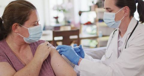 Caucasian Woman Receiving Vaccine from Nurse at Home During Pandemic