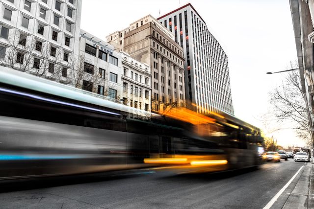 This shot captures the dynamic movement of a bus as it speeds through a city street during twilight. The motion blur effect conveys a sense of fast-paced urban life, while the surrounding tall buildings add an element of structure and modernity. Perfect for use in urban planning presentations, transport company promotions, and city tourism advertisements.