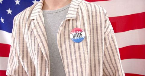 Young voter with vote badge in front of american flag