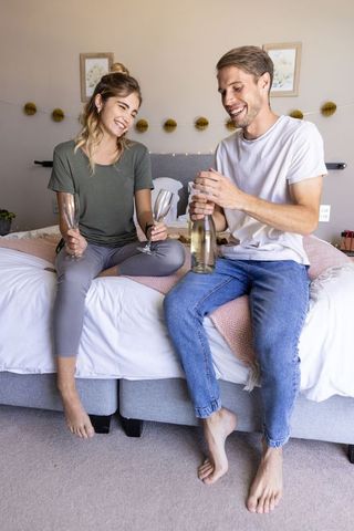Couple enjoying champagne in cozy bedroom setting