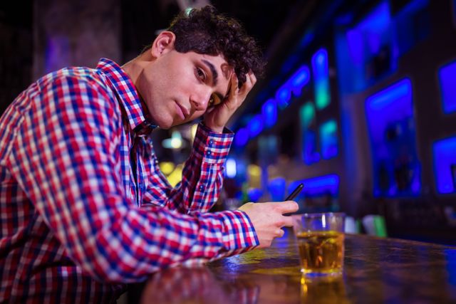 Portrait of sad young man sitting at bar counter