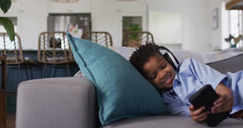 Joyful Boy with Headphones Relaxing and Playing Mobile Game