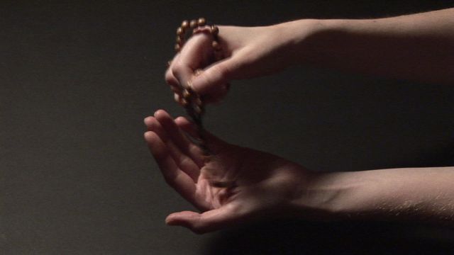 Shows dynamic of hands holding prayer beads against dark background, emphasizing theme of spirituality and devotion. Useful for illustrating concepts of meditation, personal reflection, and religious practices in blogs, articles, or promotional materials focused on spirituality and wellness.