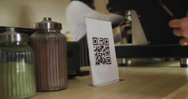 QR code standing on counter in modern coffee shop. Suitable for illustrating contactless payment systems, digital transactions, or modern business practices in cafes and small businesses.