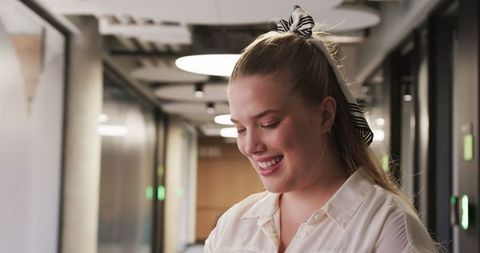 Smiling Woman in Modern Office Corridor with Natural Lighting