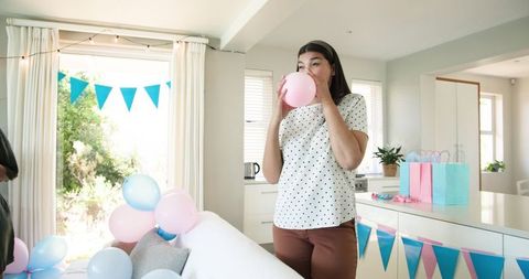 Friends decorating with balloons for baby shower in sunny room