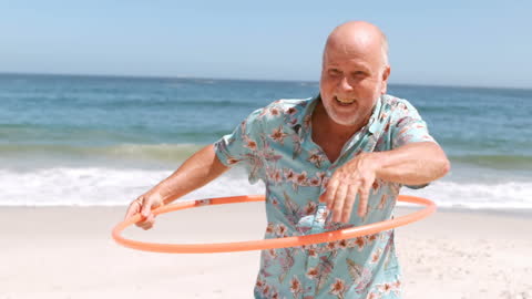 Senior Man Enjoying Hula Hoop on Beach Vacation