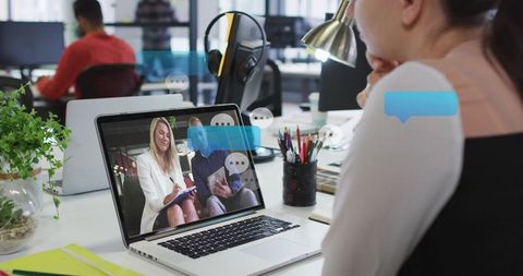 Woman watching laptop during remote meeting in modern coworking office with chat bubbles
