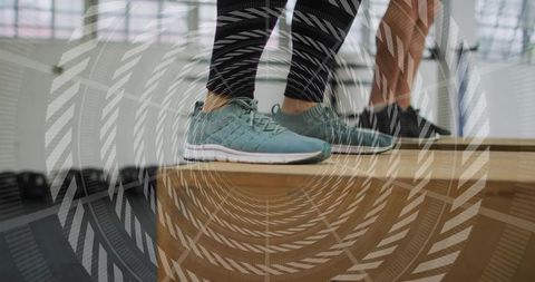 Teal sneakers balancing on wooden plyo box during partner balance training in gym