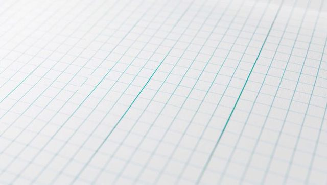 Displaying diagonal graph paper with three teal marker strokes, closeup grid texture