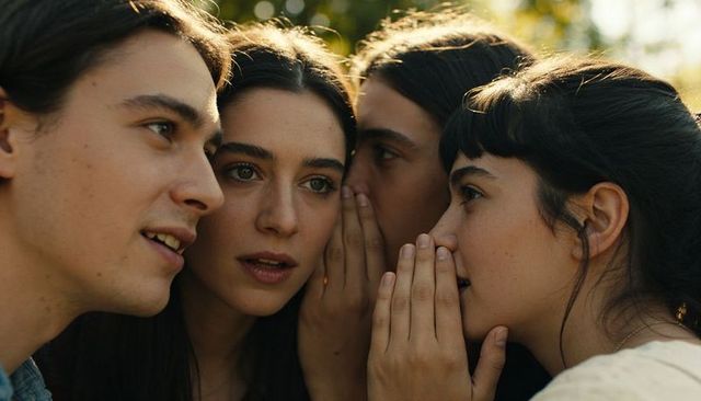 Whispering friends sunlit garden intimate outdoor conversation among young adults