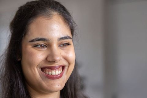 Young indian woman smiling with natural makeup and stud earring closeup headshot beauty