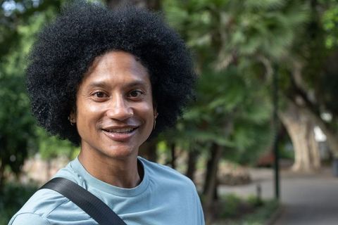 African american man smiling on park walkway with backpack, casual outdoor portrait