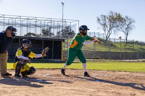 Batter bunting at home plate, catcher squatting, umpire signaling safe during baseball game