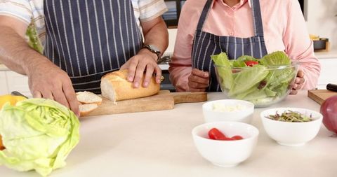 Senior Couple Preparing Salad and Bread in Domestic Kitchen