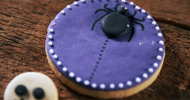 A Halloween-themed cookie decorated to resemble a spooky scene, with a purple background and a black spider, with copy space. Its detailed icing work makes it not only a treat but also a festive decoration for the holiday.