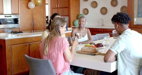 Diverse friends enjoying dining table conversation and snacks
