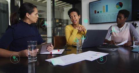 Female Team Collaborating in Modern Boardroom Presenting Sales Data on Laptop and Monitor