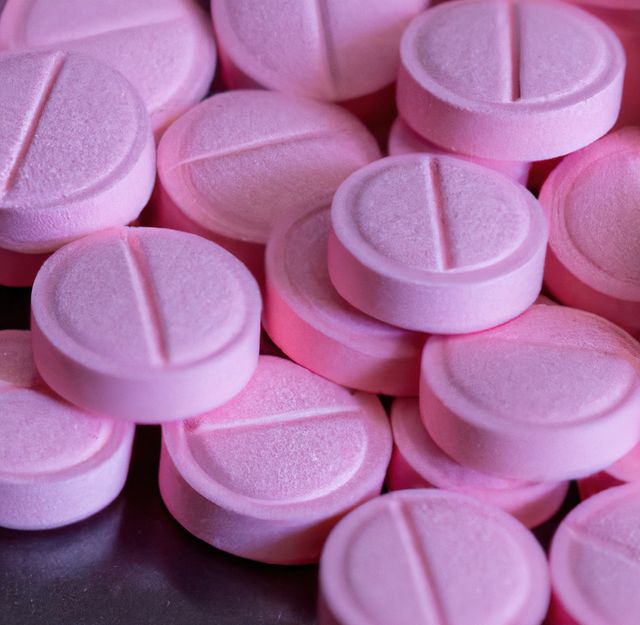 Close up of multiple round pink pills on black background. Medicine, healthcare and treatment concept.
