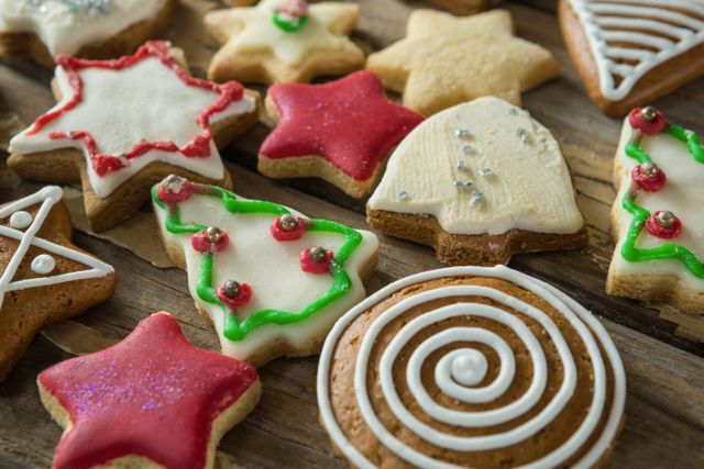 Close-up of various decorated gingerbread cookies arranged on a rustic wooden plank. Ideal for holiday-themed promotions, baking blogs, festive greeting cards, and seasonal recipe books.