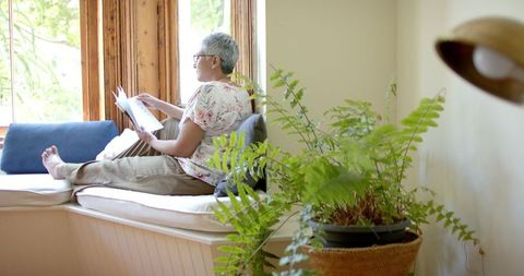 Senior Woman Relaxing with Book by Window