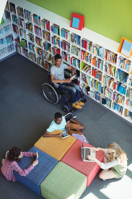 Shows four students of different backgrounds studying together in a school library. One student is using a wheelchair, emphasizing inclusivity. Ideal for educational content, diversity-related topics, and inclusive learning environments.